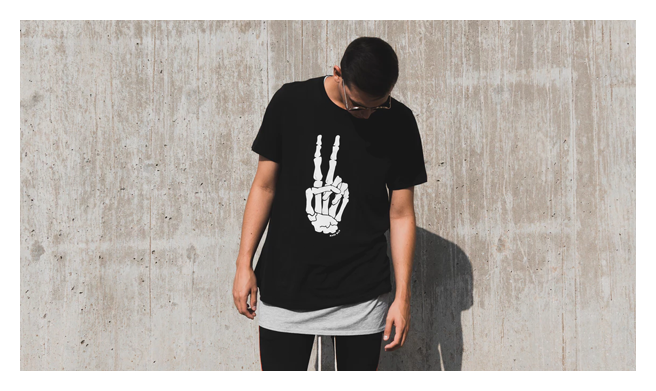 Model wearing sunglasses looking down wearing a skeleton peace symbol t-shirt